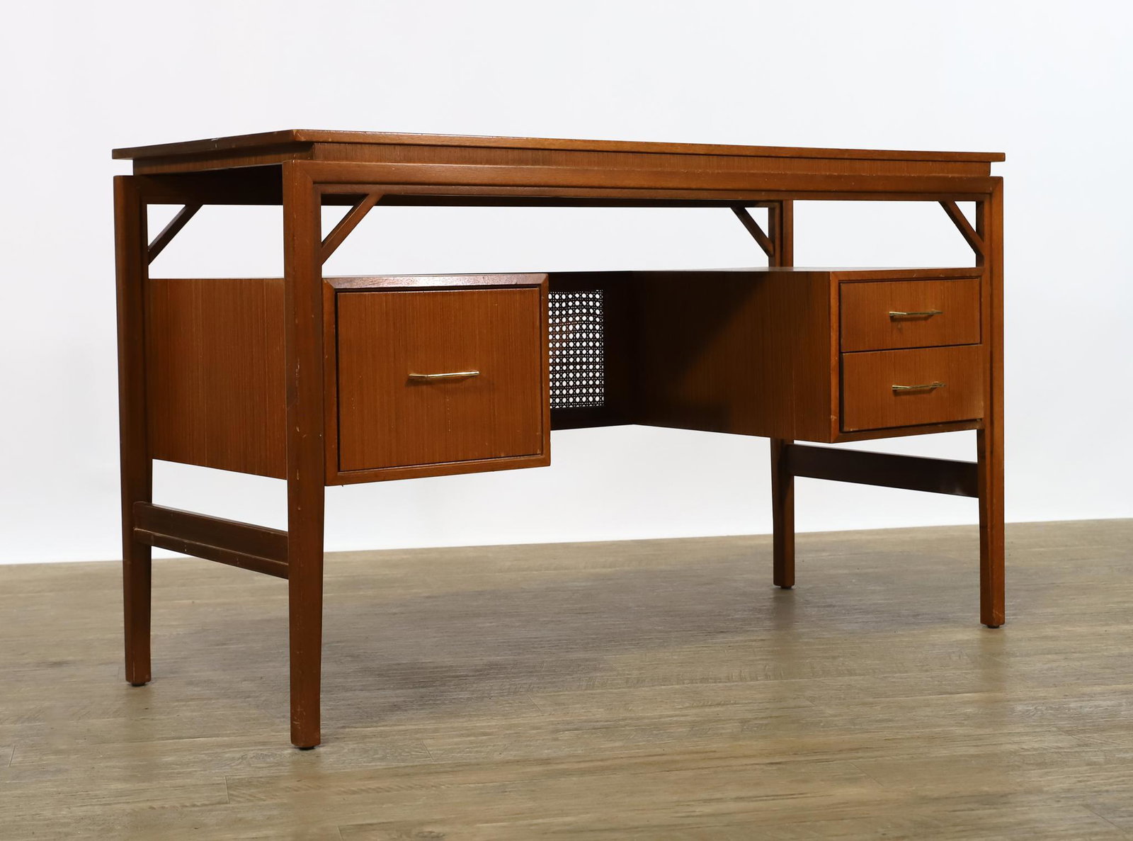 Danish Modern Teak Desk: Floating top desk with three drawers and caning, on tapered square legs, illegible stamp to the bottom of a drawer. There is a drill hole to the top and other surface wear including staples to the bac