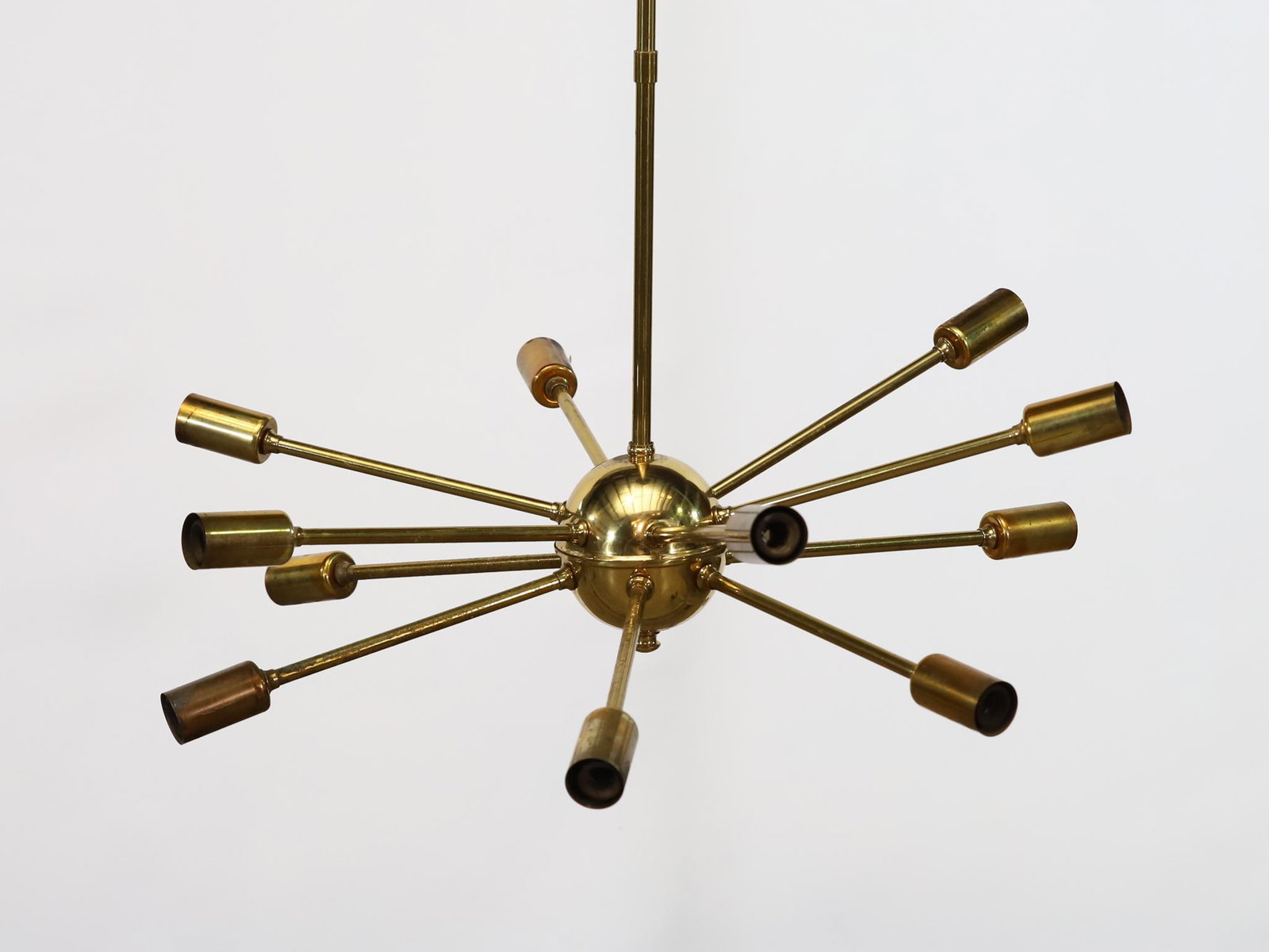 Space Age "Sputnik" Pendant Light: In the manner of Gino Sarfetti, brass 12-light hanging pendant lamp. One missing socket; one torn socket; the central ball has some warping. The electrical wiring has been cut at ceiling length; not t