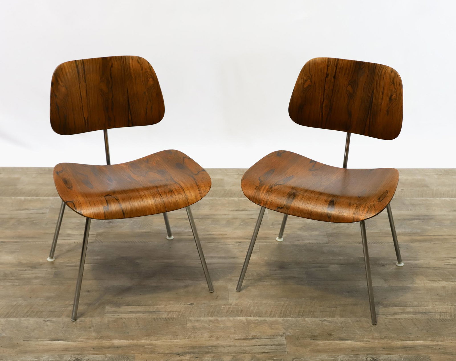 Charles and Ray Eames for Herman Miller Rosewood DCM Chairs: Molded plywood dining chairs, pair, with rosewood veneer and chrome base, labeled. Each is missing the front feet glides, but a loose glide is included. 29.5"h x 19.5"w x 20"d, seat height of 17" **Pl