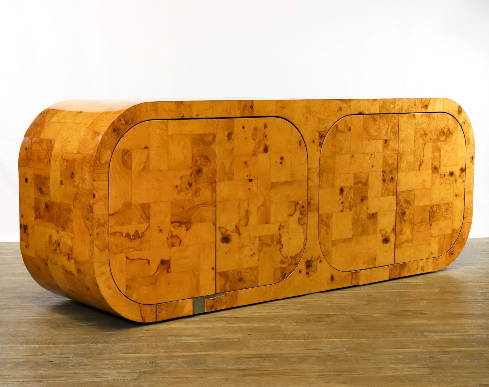 Paul Evans for Directional Cityscape Credenza: Patchwork burl veneer, with curved sides, and two cabinets which press open to reveal interior shelves. Unsigned. Some veneer loss to the lower front. The top shows some stains and light scratches. 32
