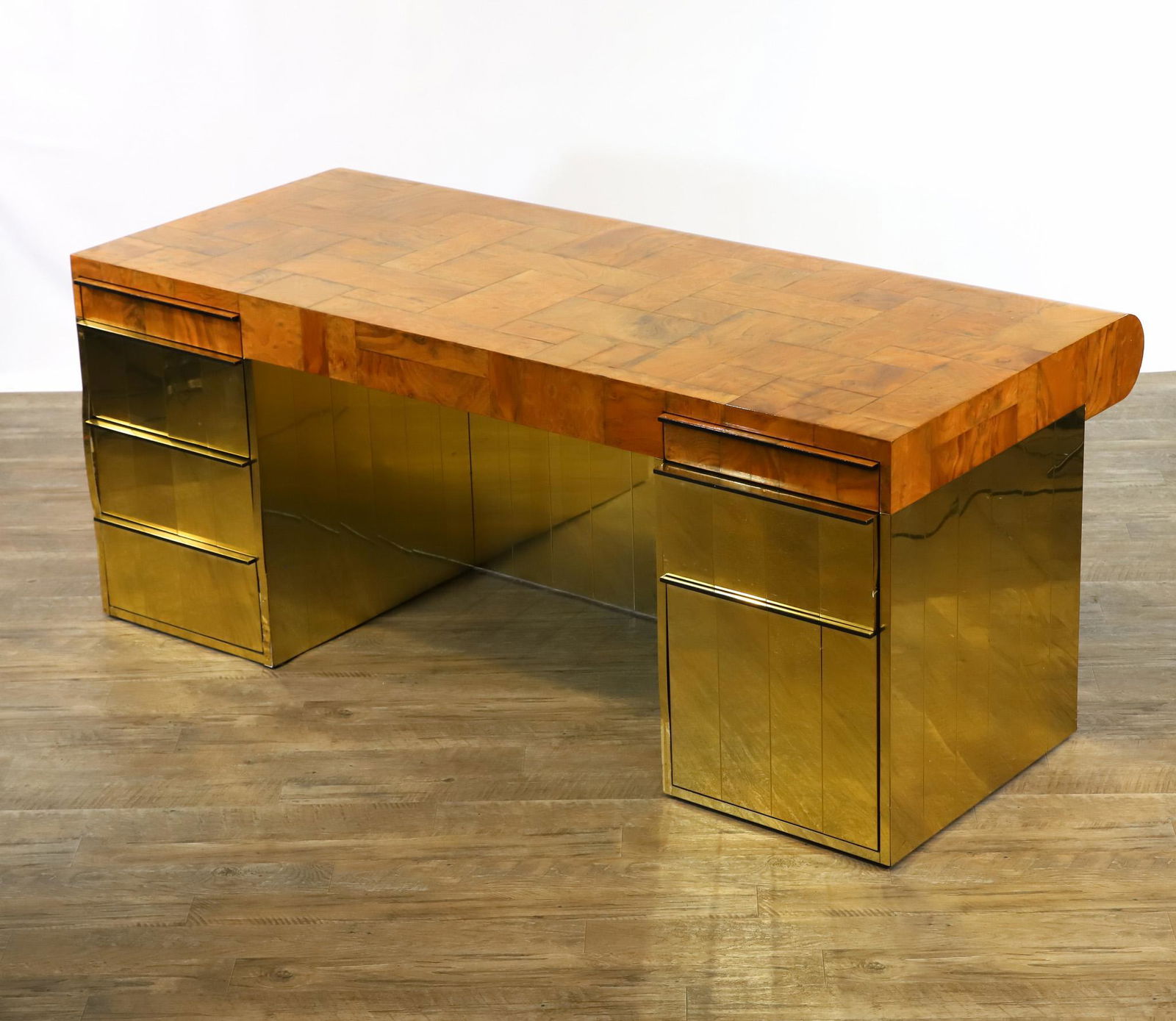Paul Evans for Directional Cityscape Executive Desk: Patchwork burl veneer top with curved front, on goldtone veneer base, with seven drawers. Signed upper center front. Some of the goldtone veneer is partly detached and/or damaged, and there is crazing