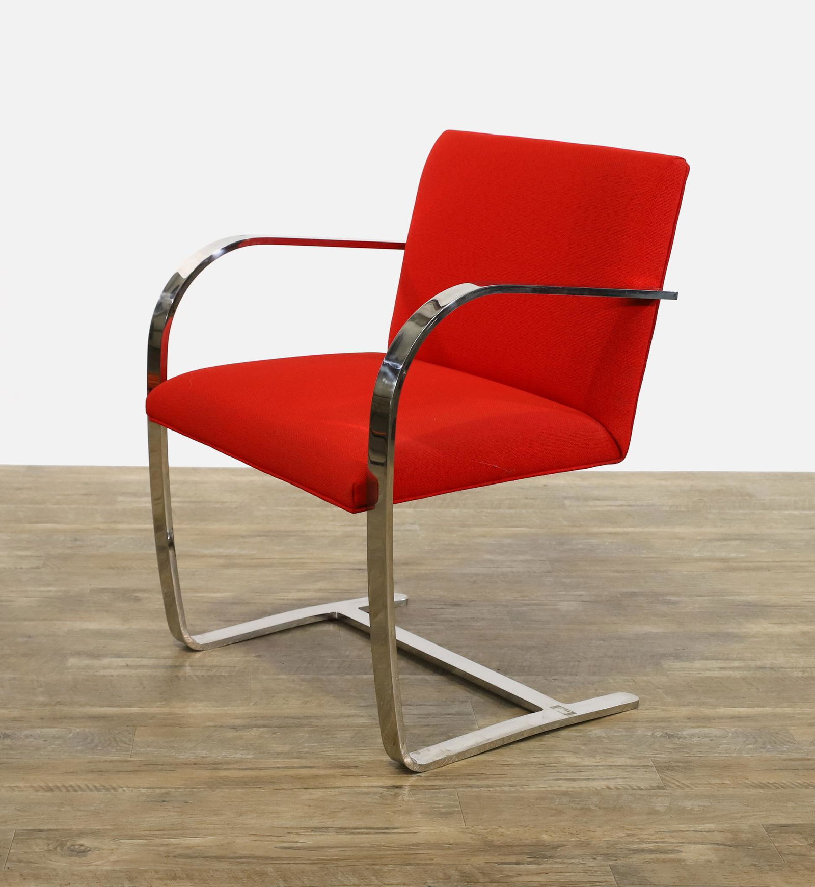 Mies van der Rohe for Knoll BRNO Chair: Polished chrome flat bar cantilever armchair with red upholstery, marked. One seat corner screw is not fastened to the frame and needs replacing or repair. 31"h x 23"w x 20"d, seat height of 15" **Ple