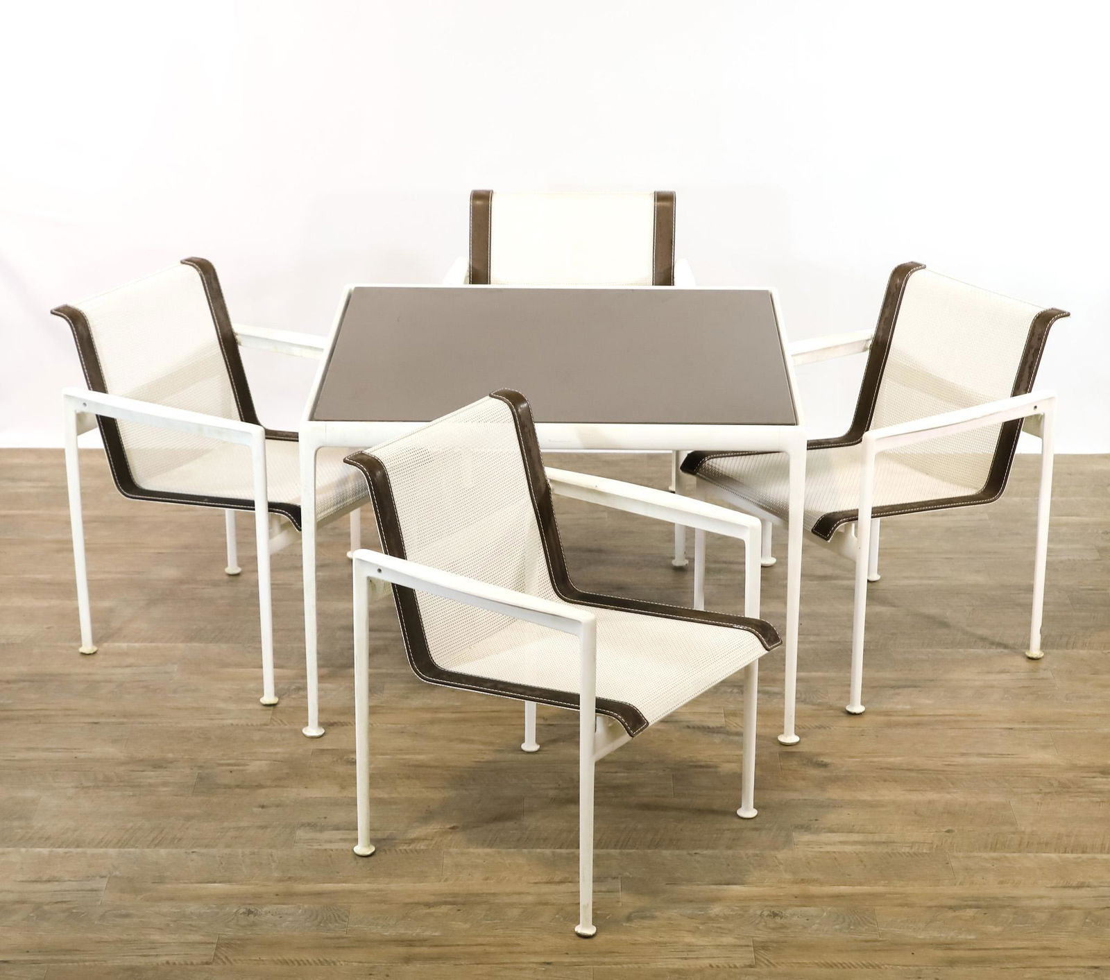 Richard Schultz for Knoll 1966 Collection Patio Furniture: Dining table with white powder coated aluminum base and black porcelain enamel steel top, 26"h x 38"w x 38"d. Set of (4) dining armchairs, with powder coated aluminum frames and woven vinyl coated pol