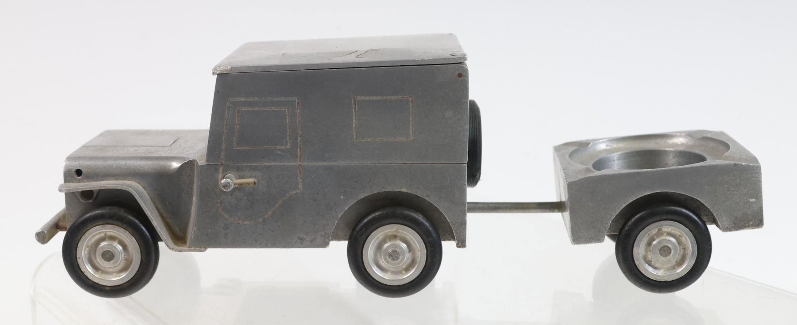Walter Baier Jeep Smoking Set: Postwar German "trench art", aluminum table lighter and cigarette box in the form of a Willys Jeep, with a trailer form ashtray. Not tested. Jeep 3"h x 5"w x 3"d, overall 9”w