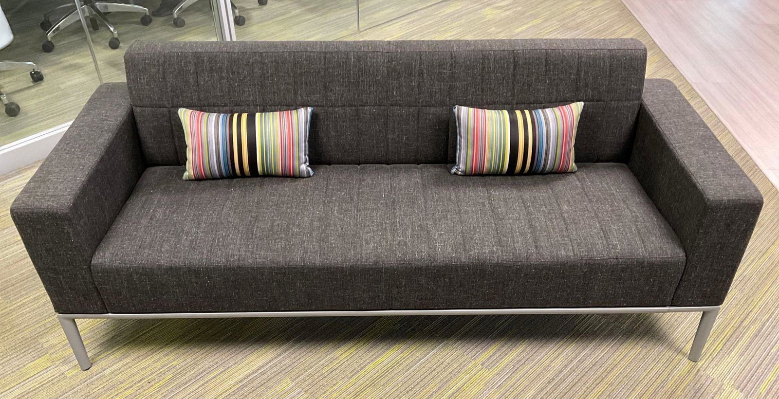 Allsteel Sofa: Allsteel sofa with charcoal grey upholstery and decorative striped pillows. Measures 75"w x 29"d x 30"h. This lot is not eligible for Alderfer transport. Buyer is responsible for bringing all necessar