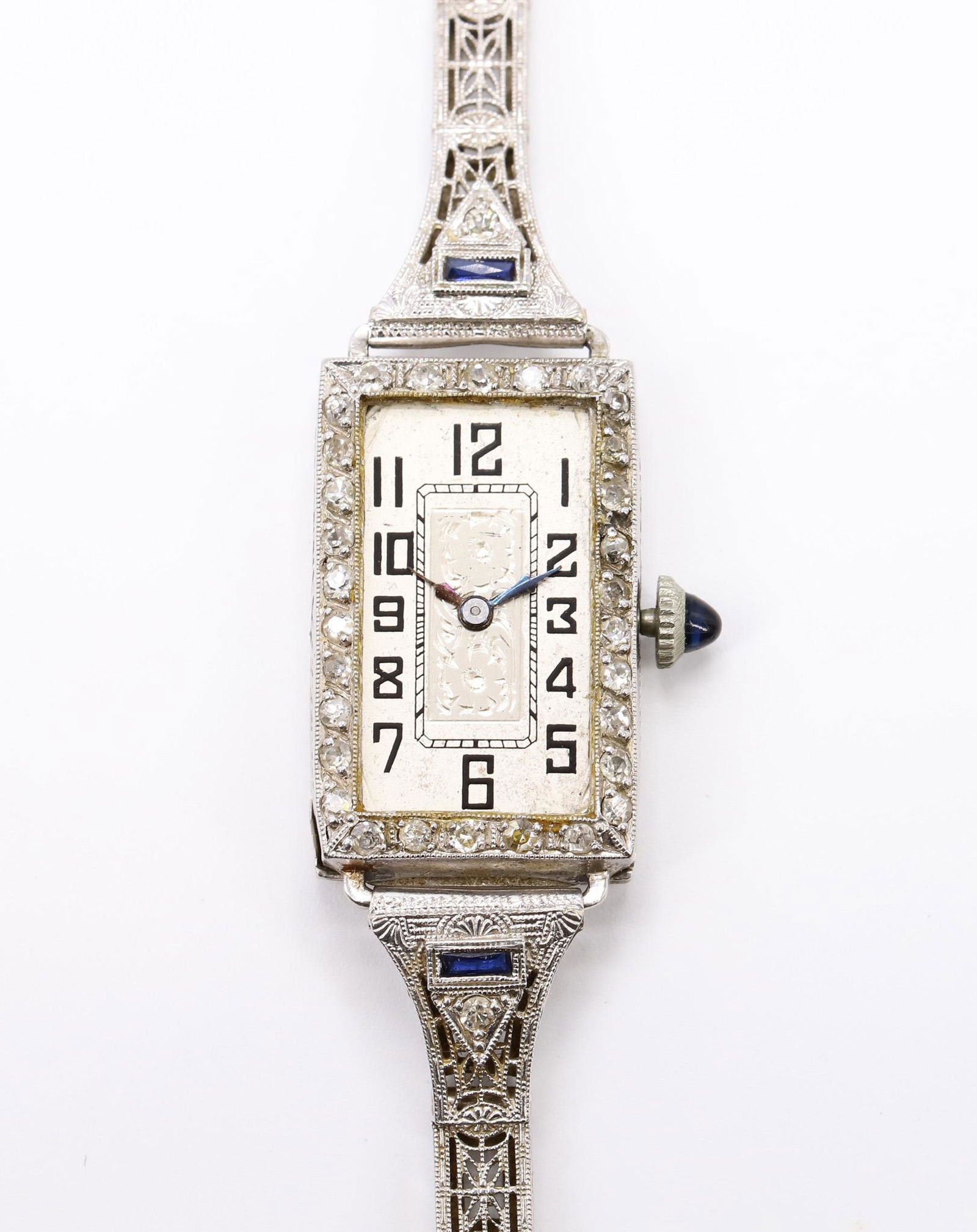 Art Deco Platinum and Diamond Invicta Wristwatch: Art deco ladies wristwatch with a diamond and platinum bezel with a 14k white gold and sapphire band. 8.6dwt with movement removed. Crystal is loose but present. 7"