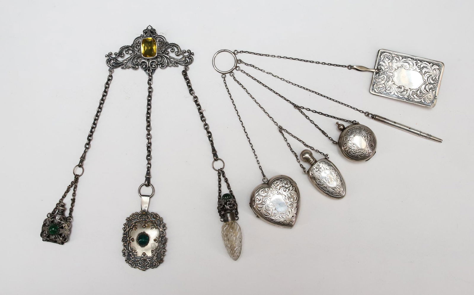 Victorian Sterling and Silver Plate Chatelaines: American sterling silver chatelaine with heart form box, perfume bottle, coin holder, mechanical pencil, and notepad, all with engraved scrollwork and marked Sterling, monogrammed. Silver plate Rococo