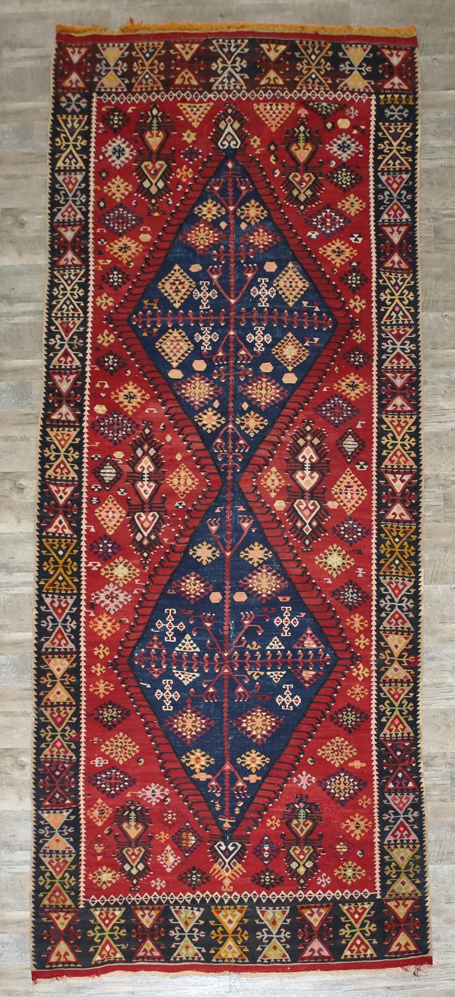 Caucasian Runner: Hand knotted with double diamond latch hook medallions, floral motifs in a red field, inverted diamond and navy blue main border. 10'7"l x 4'7"w