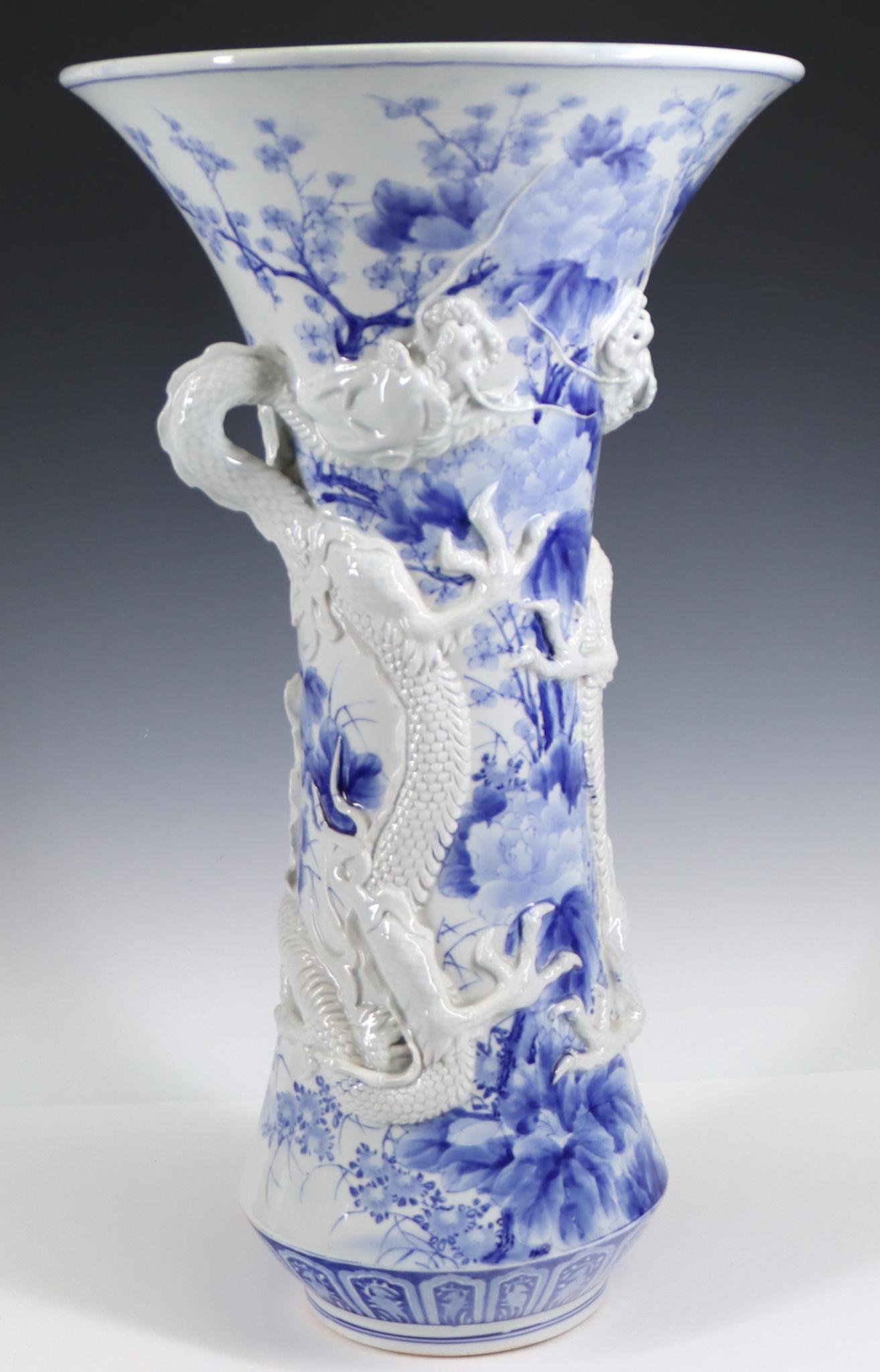 Japanese Hirado Porcelain Dragon Vase: Blue and white vase with flared rim and tapered foot, decorated with cherry blossoms and chrysanthemums, with double dragons in relief, unmarked, Meiji era. 21.75"h x 12.5"w