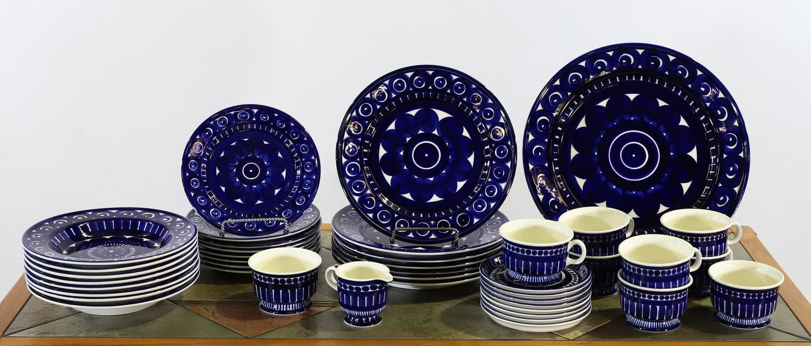 Valencia by Arabia Finland China Service for 8: Ulla Procope designed stoneware with hand painted midnight blue geometric decoration, including 10" dinner plates, salad plates, soup bowls, coffee cups, saucers, 13" chop plate, sugar, and creamer. I