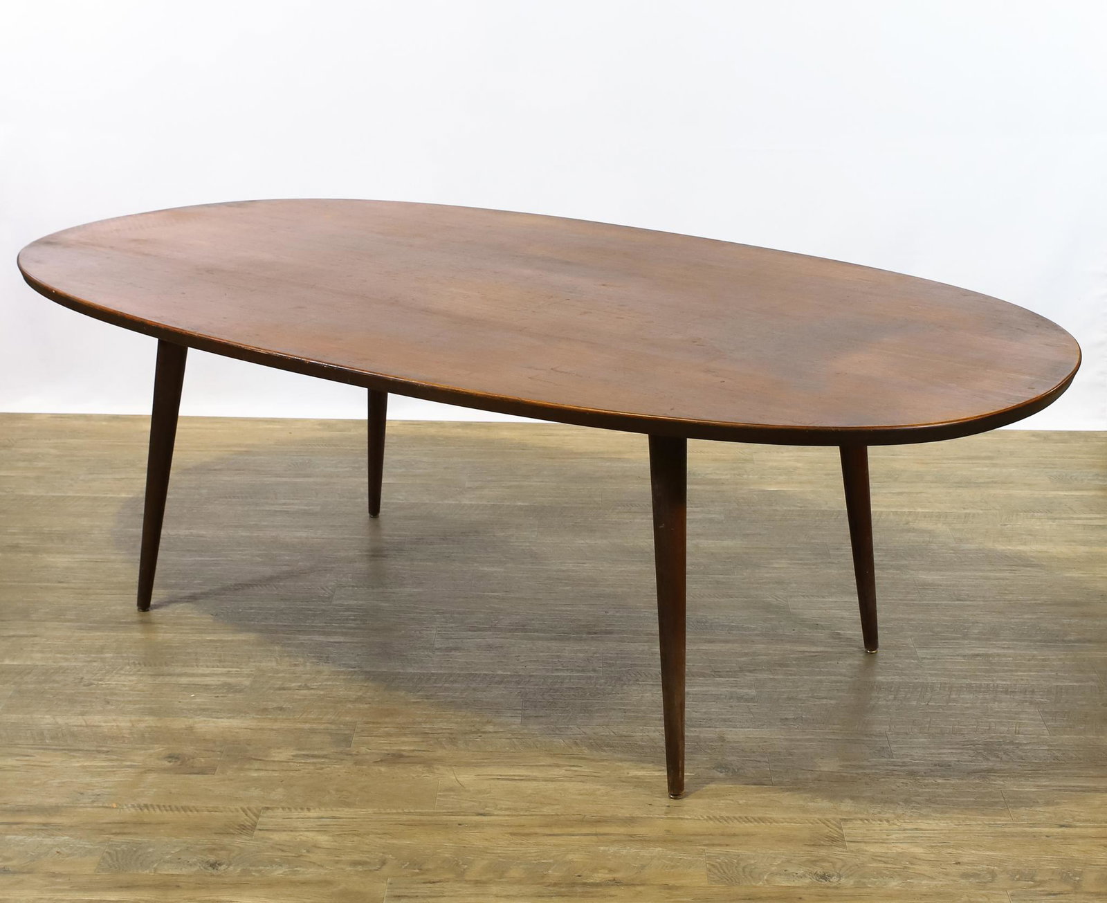 Danish Teak Dining Table: Elliptical top with tapered legs. Unmarked. Top exhibits overall usage wear. 27"h x 83"w x 46.25"w