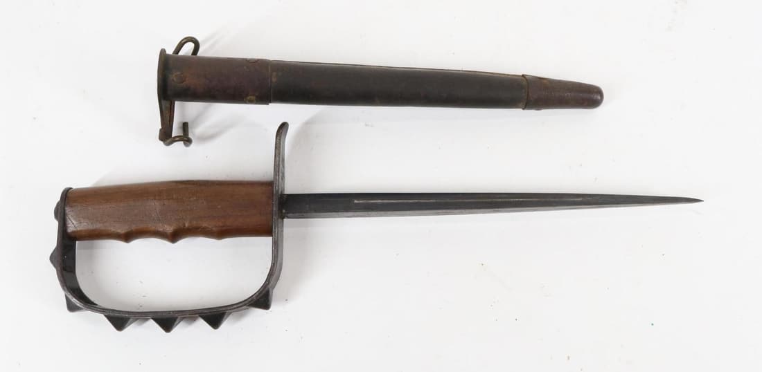 US LF&C 1917 WWI Knuckle/Trench Knife: 9 1/4" triangular blade, steel cross guard and knuckle bow with 7 stamped pyrmidal studs marked in 3 lines on underside of cross guard U.S. / LF&C / 1917, wood finger groove handle in tubular leather 