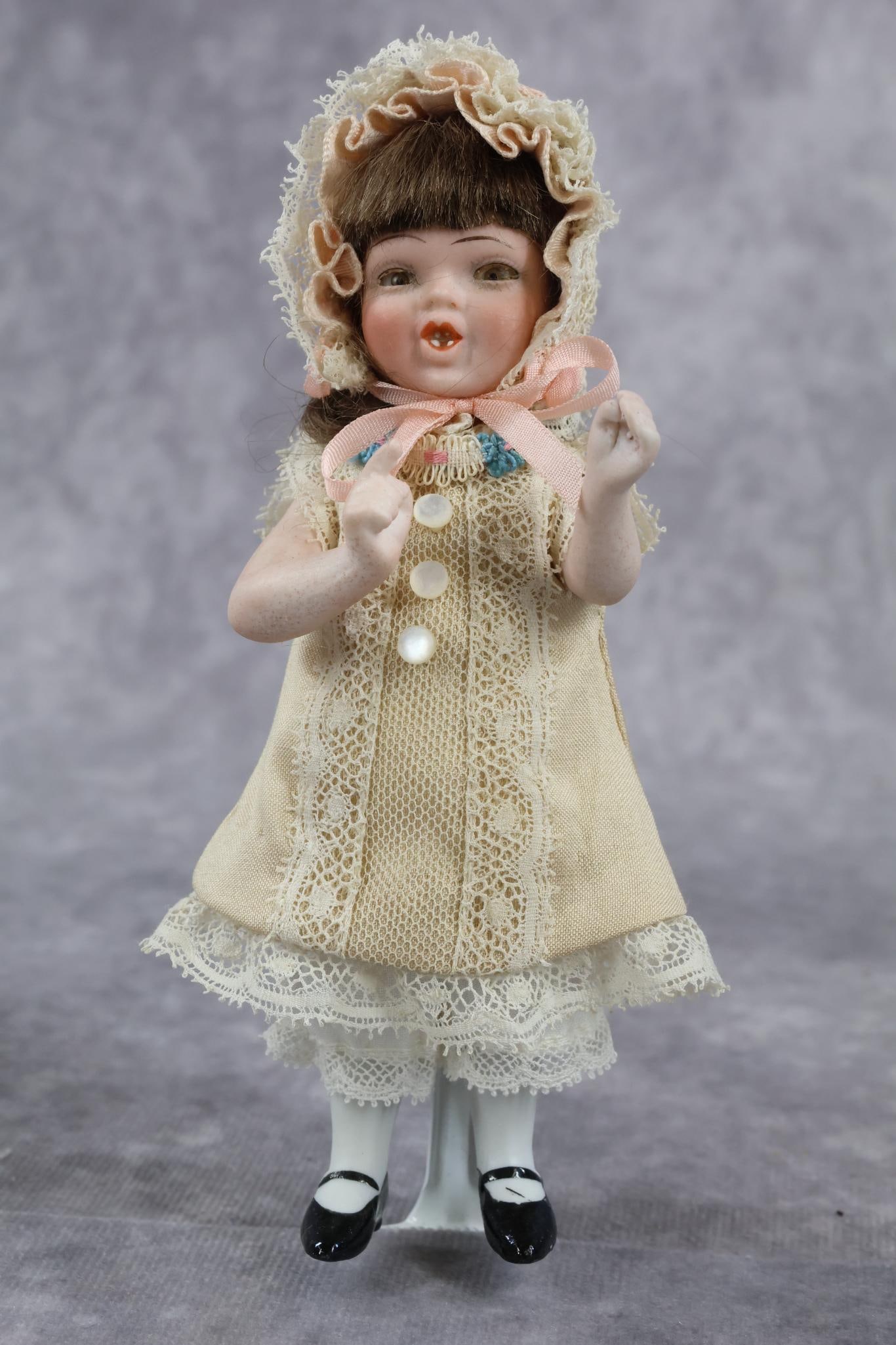 GERMAN ALL BISQUE DOLL(S).: ORSINI Character girl with glass eyes. 5" Doll "MiMi" with paper label on chest. Copr. 1920 J.J. Orsini. Back is marked JJO (copyright) 1920 44. Doll has stationary hazel eyes, brown mohair wig, open/