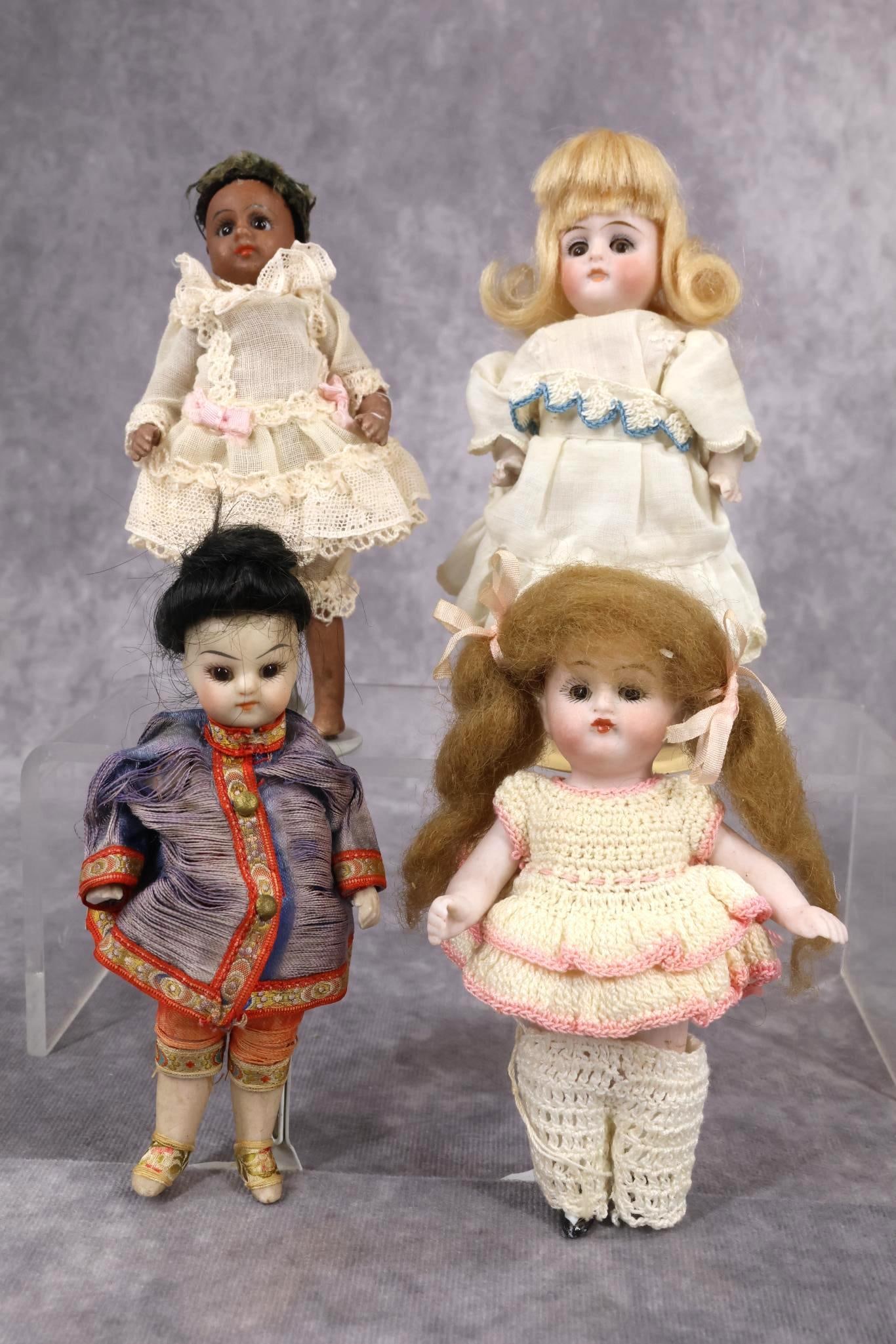 GERMAN ALL BISQUE DOLL(S).: LOT of (4) dolls. All of the dolls have glass eyes, mohair wigs, are dressed in antique/vintage clothing. 5" Unmarked Black doll and 4 1/2" unmarked Japanese doll both have stationary eyes, swivel nec