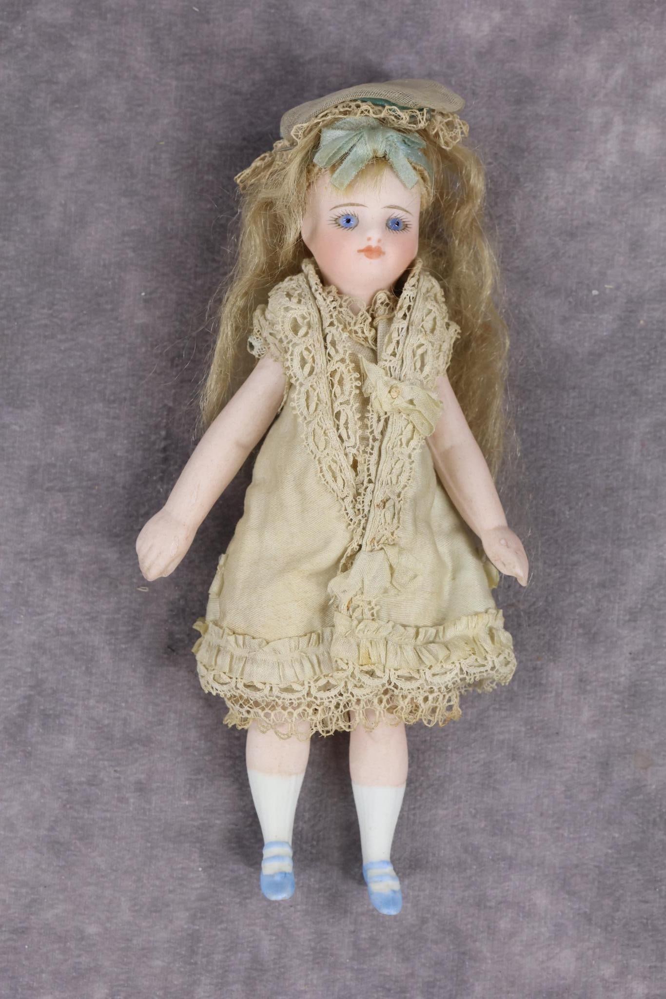 ALL BISQUE MIGNONETTE/TYPE.: 6" Unmarked solid dome doll. Stationary blue eyes, closed mouth, long blonde mohair wig. 5 Pc. slender body with swivel neck. Painted pale blue two-strap heeled shoes, white socks. Dressed in all orig