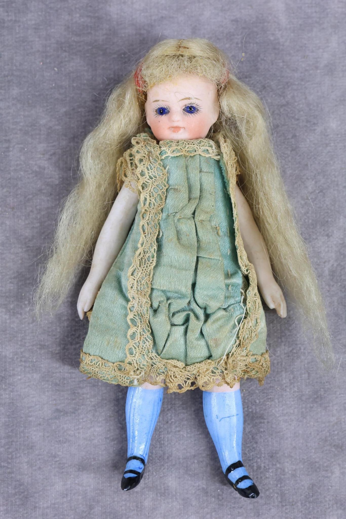 ALL BISQUE MIGNONETTE/TYPE.: 4 1/2" "5" Doll with stationary blue eyes, closed mouth, long blonde mohair wig. 5 Pc. slender body with swivel neck. Painted two-strap black heeled shoes, blue knee socks. Dressed in original aqua si