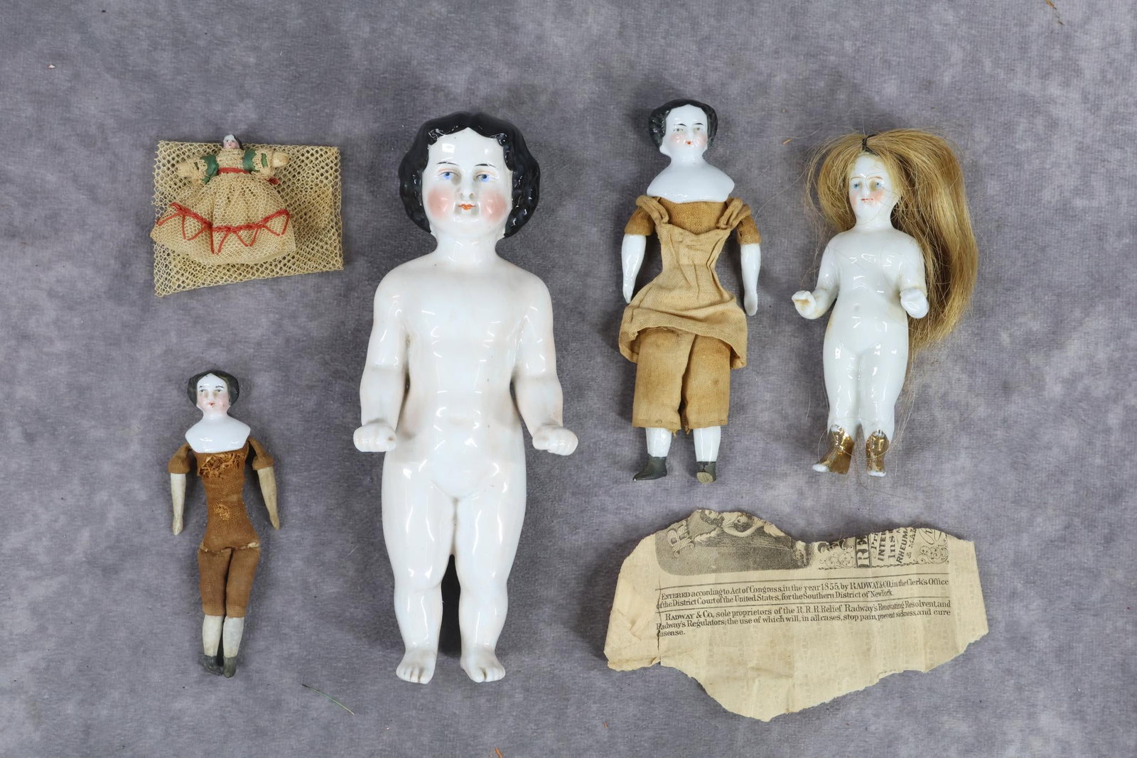 CHINA DOLL(S).: LOT of (5) dolls. (2) Frozen Charlotte dolls. 7" Pink tint with painted black hair. 4" Doll with human hair wig, painted gold boots. Condition: left elbow has been repaired. (2) Shoulder head dolls wi