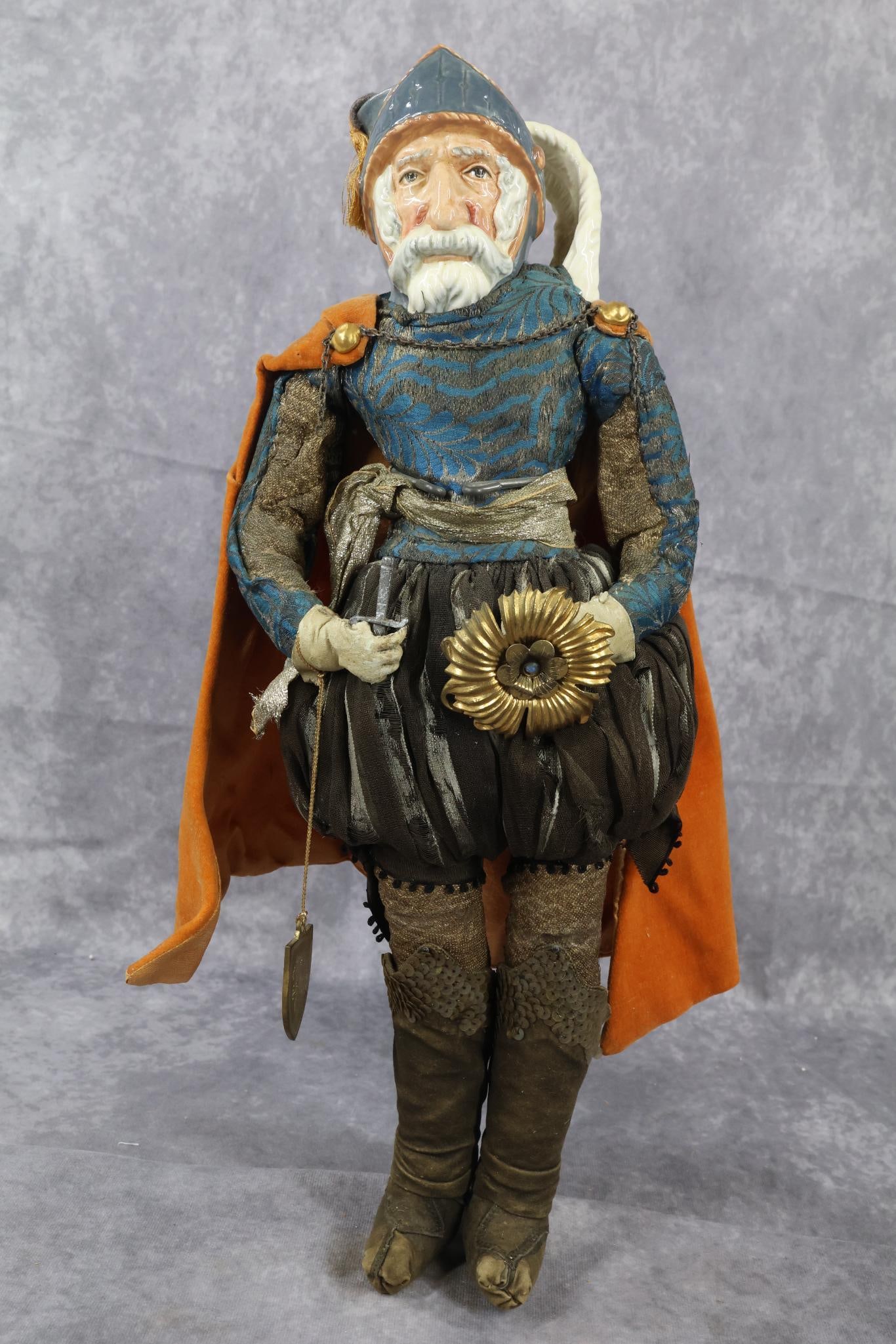 CHINA DOLL - NOVELTY.: This is an Artist doll with a ROYAL DOULTON china TOBY MUG character head of "Don Quixote". 17 1/2" T. This doll has been very well done. Cloth body, leather gloved hands, boots. Beautifully dressed i