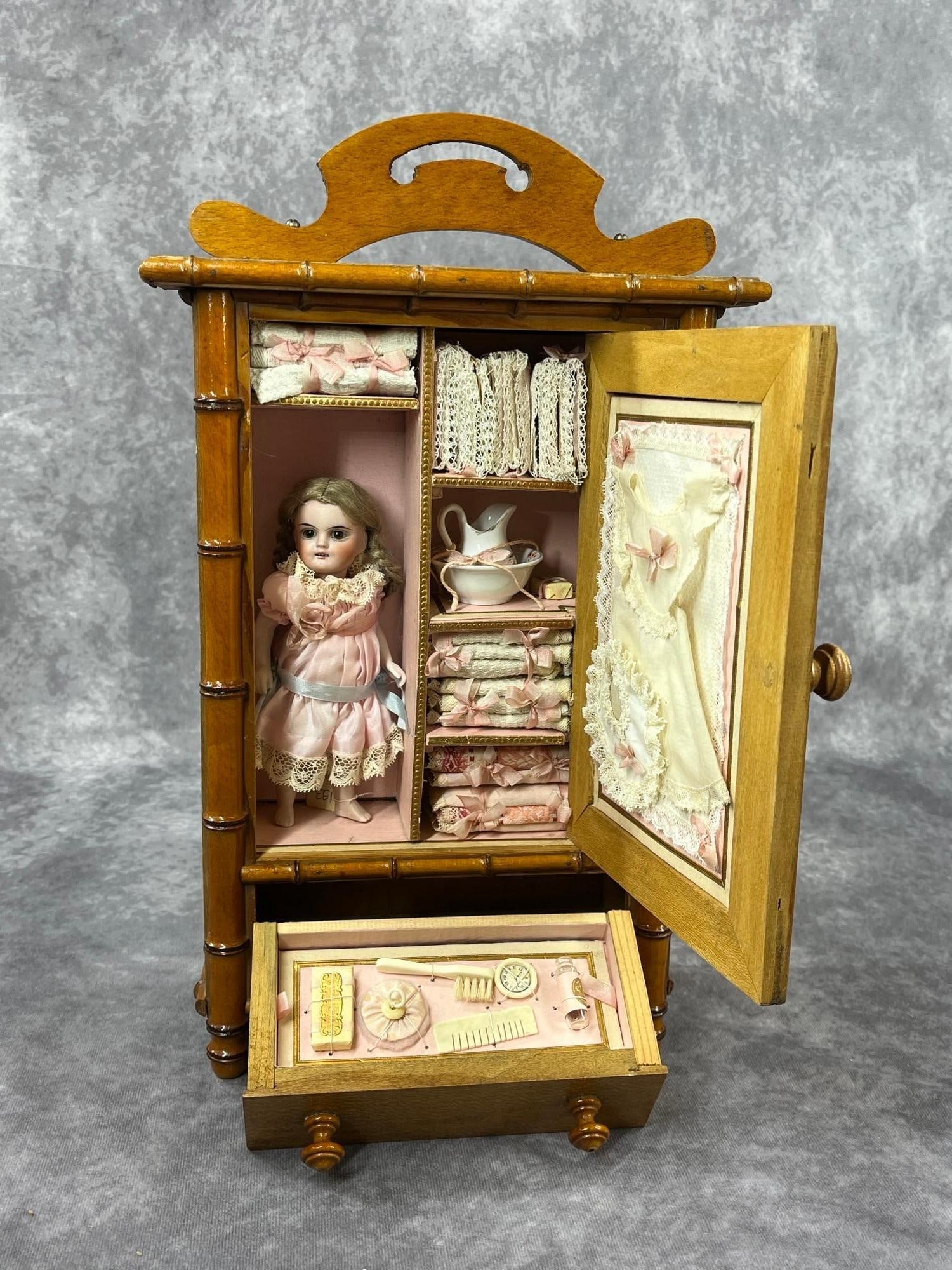 GERMAN ALL BISQUE IN PRESENTATION CABINET.: LOT. 6 1/2" 133 8 Doll with brown sleep eyes, open mouth, tosca mohair braided wig. 5 Pc. peg strung body with swivel neck, bare feet. Dressed in newer pink silk dress. Condition: nothing observed on