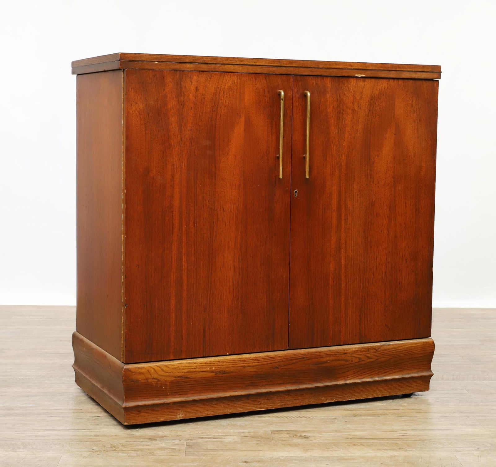 Henry P. Glass Bar Cabinet: Walnut dry bar with expandable lacquered top, the two door cabinet opens to shelving and a drawer, labeled for Saginaw Furniture Shops and Henry P. Glass. Surface wear including scratches and scuffs.
