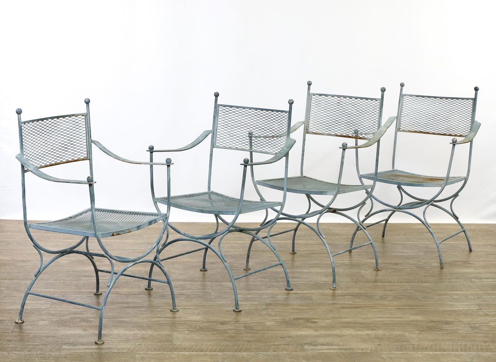 Wrought Iron Patio Chairs: Powder coated iron mesh seats and backs with curule bases and ball finials, unmarked. Surface wear including areas of paint loss and oxidation. 34.5"h x 21.5"w x 19"d, seat height 17"