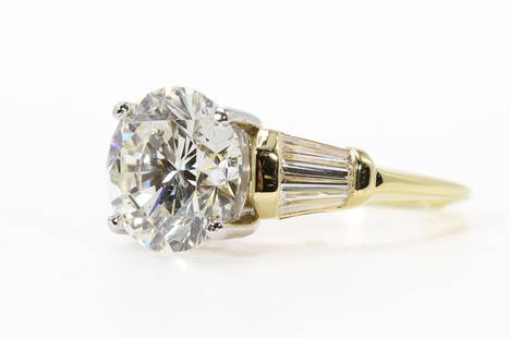 4.37 Carat Diamond Ring: 4.37 carat round brilliant cut diamond, SI2-I1 clarity and J-K color, flanked by (6) tapered baguette diamonds weighing approx. 1 carat. Setting is 14k yellow gold with (4) white gold prongs.