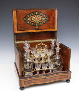 Baccarat Tantalus: French, late 19th - early 20th C., serpentine tantalus with burl and crossbanded mahogany bordered by ebony inlay banding, decorated to the front and top with mother of pearl, brass, and ebony arabesq