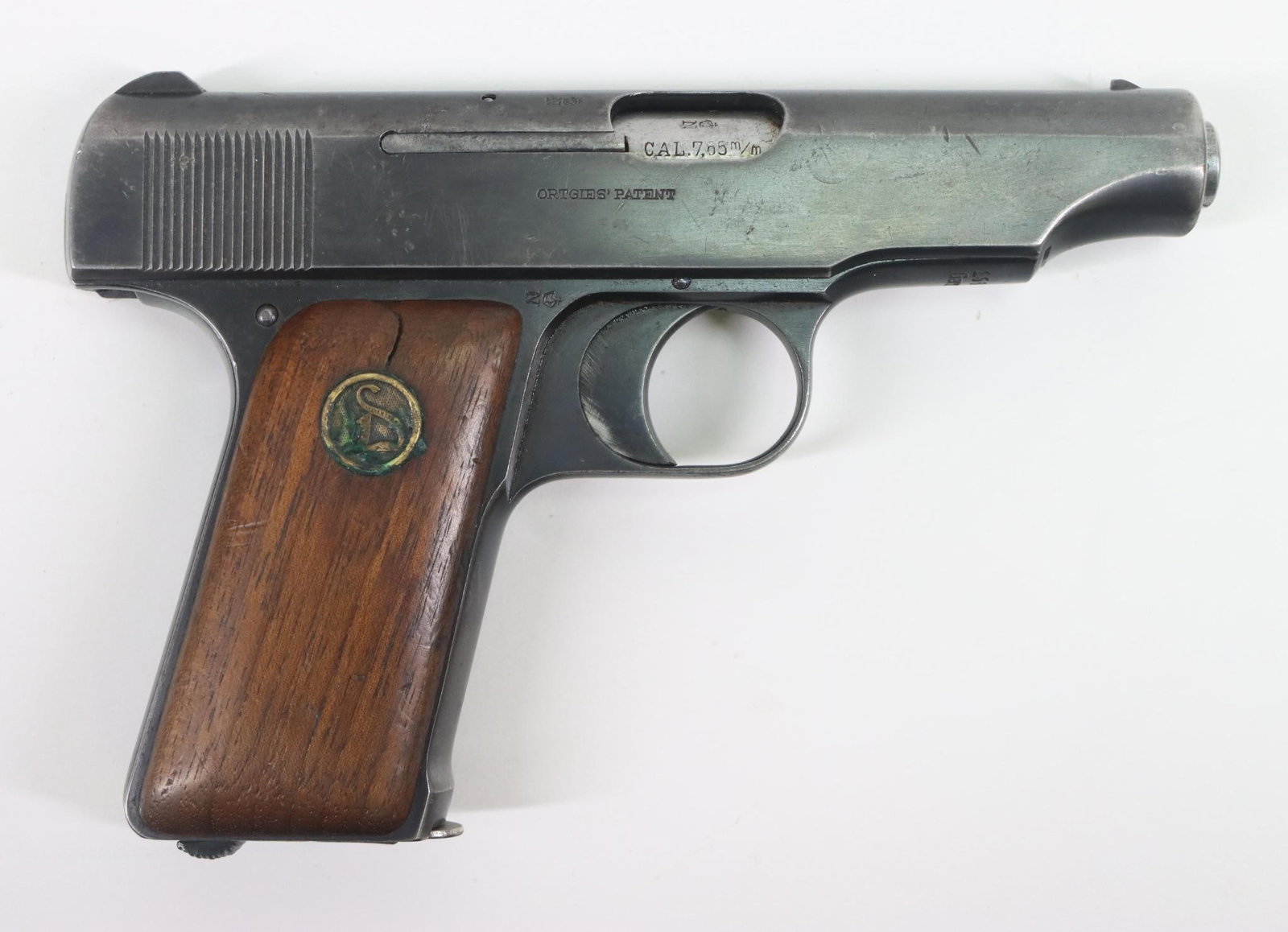 Papered War Trophy Deutsche Werke Ortgies Patent Semi Automatic Pistol: 7.65mm, 3 1/2" bbl, SN 156637. 85% blue finish shows general thinning, good bore, wood grips show average handling with small crack in right scale above medallion, 1-7 rnd magazine and Military captur