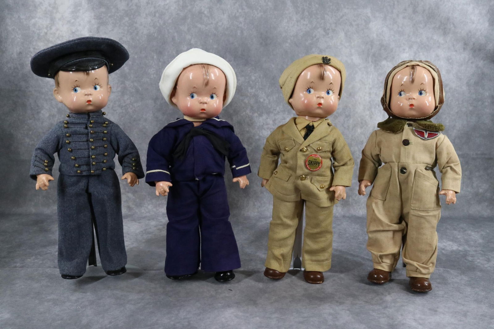 COMPOSITION - EFFANBEE.: LOT of (4) 14" "Skippy" Military dolls. All dolls have molded, painted brown hair, blue side glance eyes. They have composition heads, arms and lower legs with cloth torsos. Molded shoes, socks. Doll