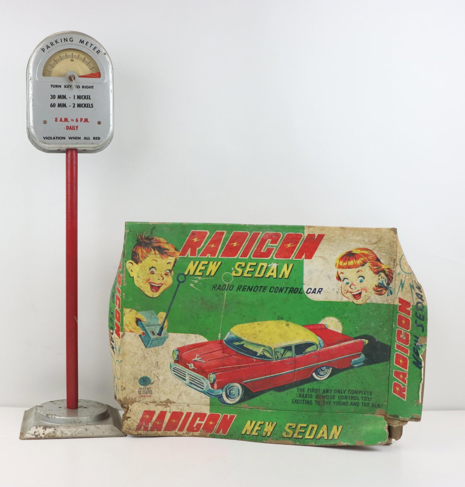 Modern Toys Radicon New Sedan & Parking Meter: Motor Toys Japan, Radicon New Sedan set, tin sedan and radio remote control, original box in fragile condition. Pressed steel parking meter bank and toy, 3 pieces, 24.5”h total, wind-up up timer