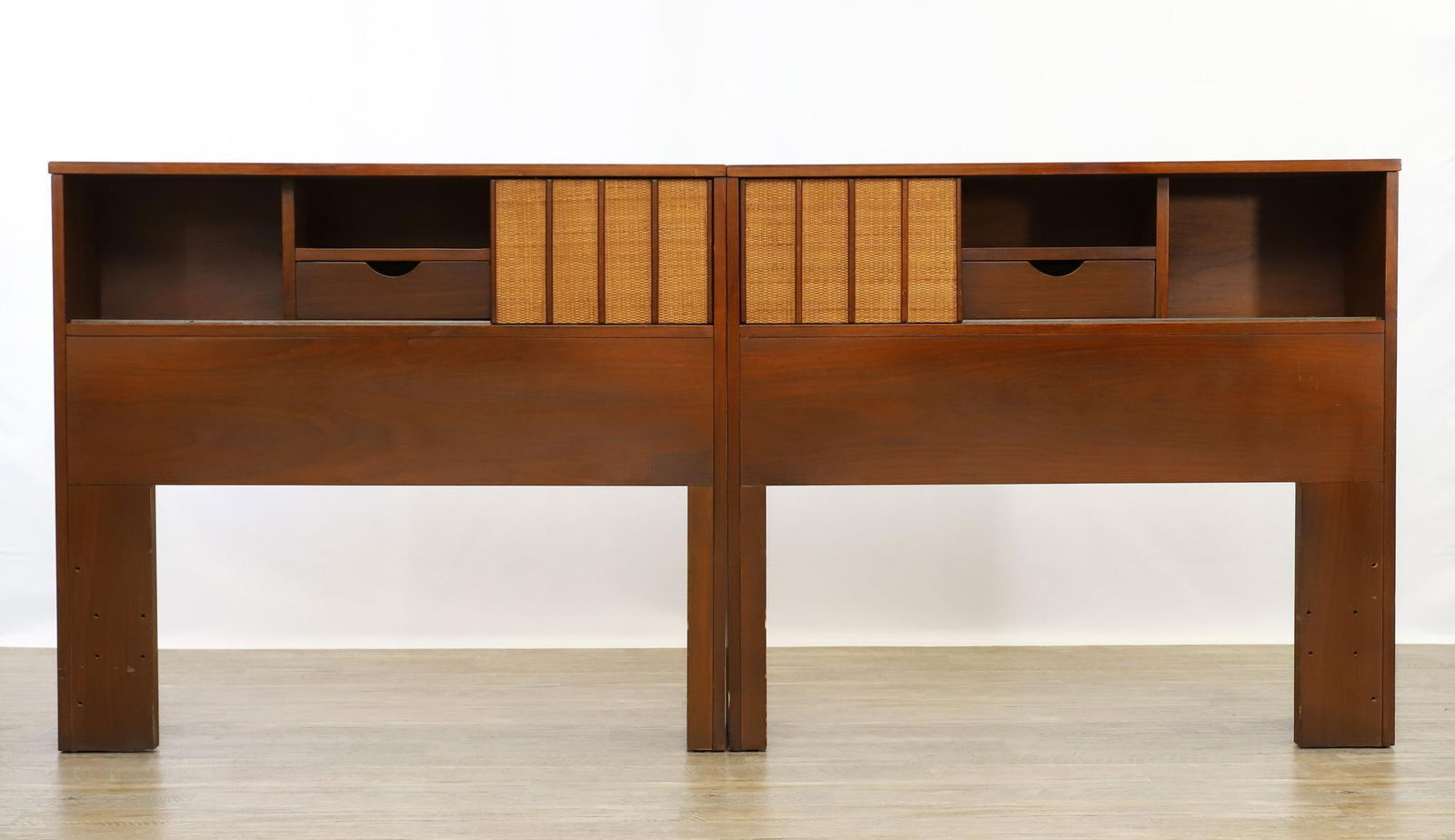 Mainline by Hooker Bed Headboards: Walnut headboards, each with a drawer and open compartment flanked by larger open compartments, featuring a sliding cane front door, model no. 436. Can be used separately for two twin beds, or togethe