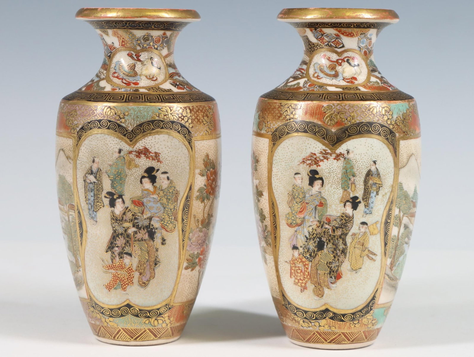 Moriyama Japanese Satsuma Pottery Vases: Meiji - Taisho era, pair of small baluster vases with panels depicting women and children, birds and flowers, landscapes, fans, and fruit, with raised gilding and geometric motifs throughout. One mark