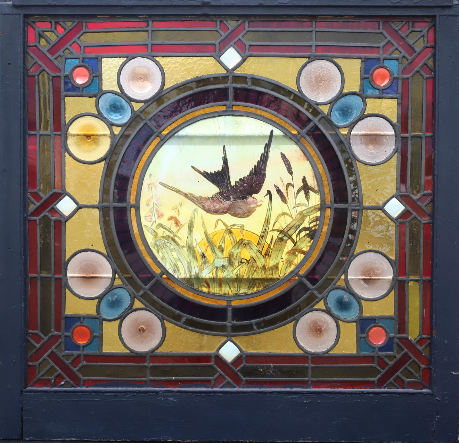 Stained Glass Window: Stained glass window with a swallow in flight surrounded by geometric and woven designs. 30.5"h x 34.5"w