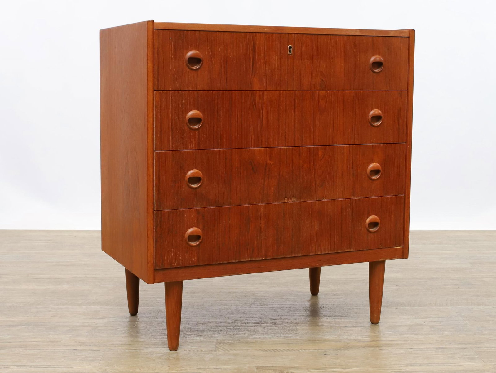 Teak Chest of Drawers: Danish Modern style teak chest of four drawers with cigar legs, in the manner of Kai Khristiansen, unmarked. Surface wear including areas of veneer damage and water stains. 31.5"h x 29.25"w x 17"d