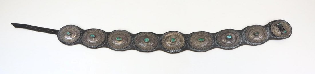 Silver Concho Belt: Leather concho belt set with (8) conchos each hand chased with a central turquoise cabochon, 3" x 2.5". No purity hallmarks noted, signed SS with an arrow, presumed Navajo. 39" overall