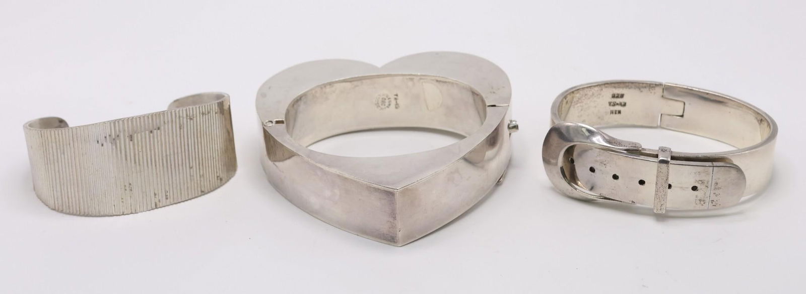Taxco Mexican Sterling Silver Cuff Bracelets: (3) Mexican Taxco sterling silver cuffs, a belt shaped cuff hallmarked TS-43, heart shaped cuff hallmarked TA-19, and a fluted cuff hallmarked illegibly. 8.00 ozt