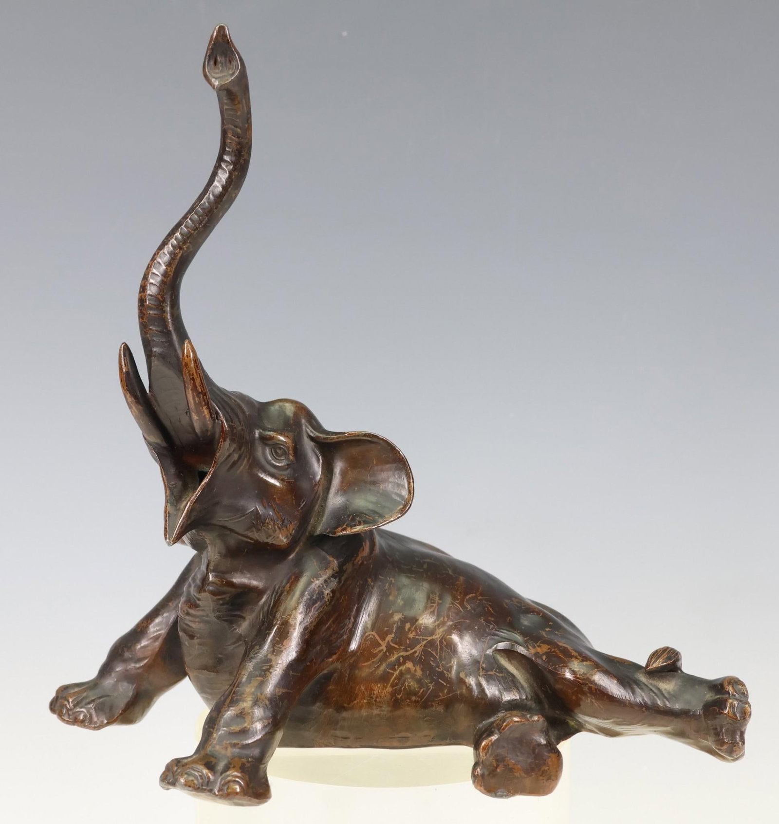 Juzan Japanese Metal Elephant Sculpture: Meiji era, bronze finished white metal sculpture of a recumbent elephant with trunk up, marked. 7.25"h x 7.5"w x 4"d