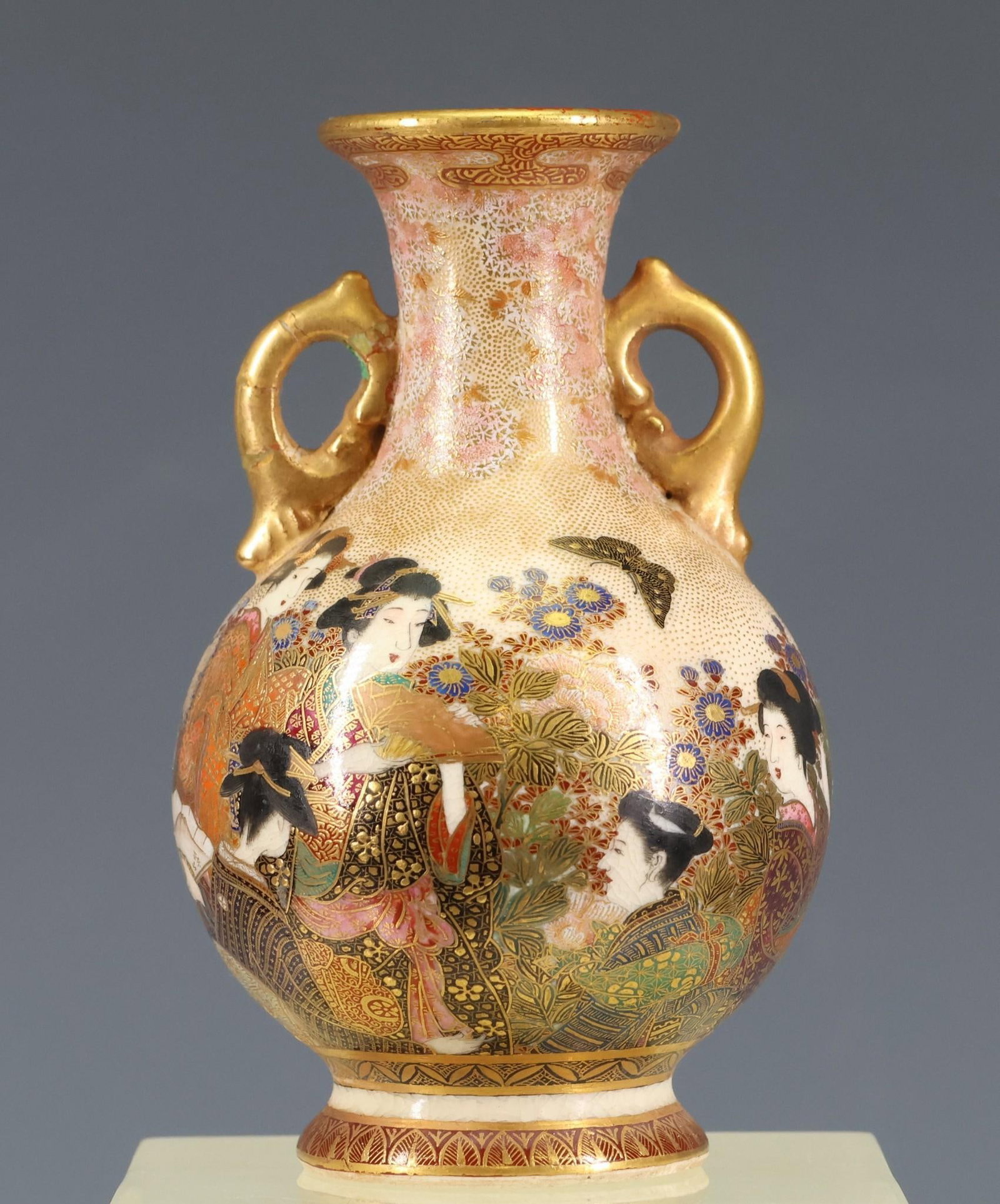 Kinzan Japanese Satsuma Pottery Miniature Vase: Meiji - Taisho era miniature vase with handles, depicting court ladies in a garden with flowers and butterflies. Marked to the foot. Repairs to the rim and a handle. 3.5"h x 2.25"w