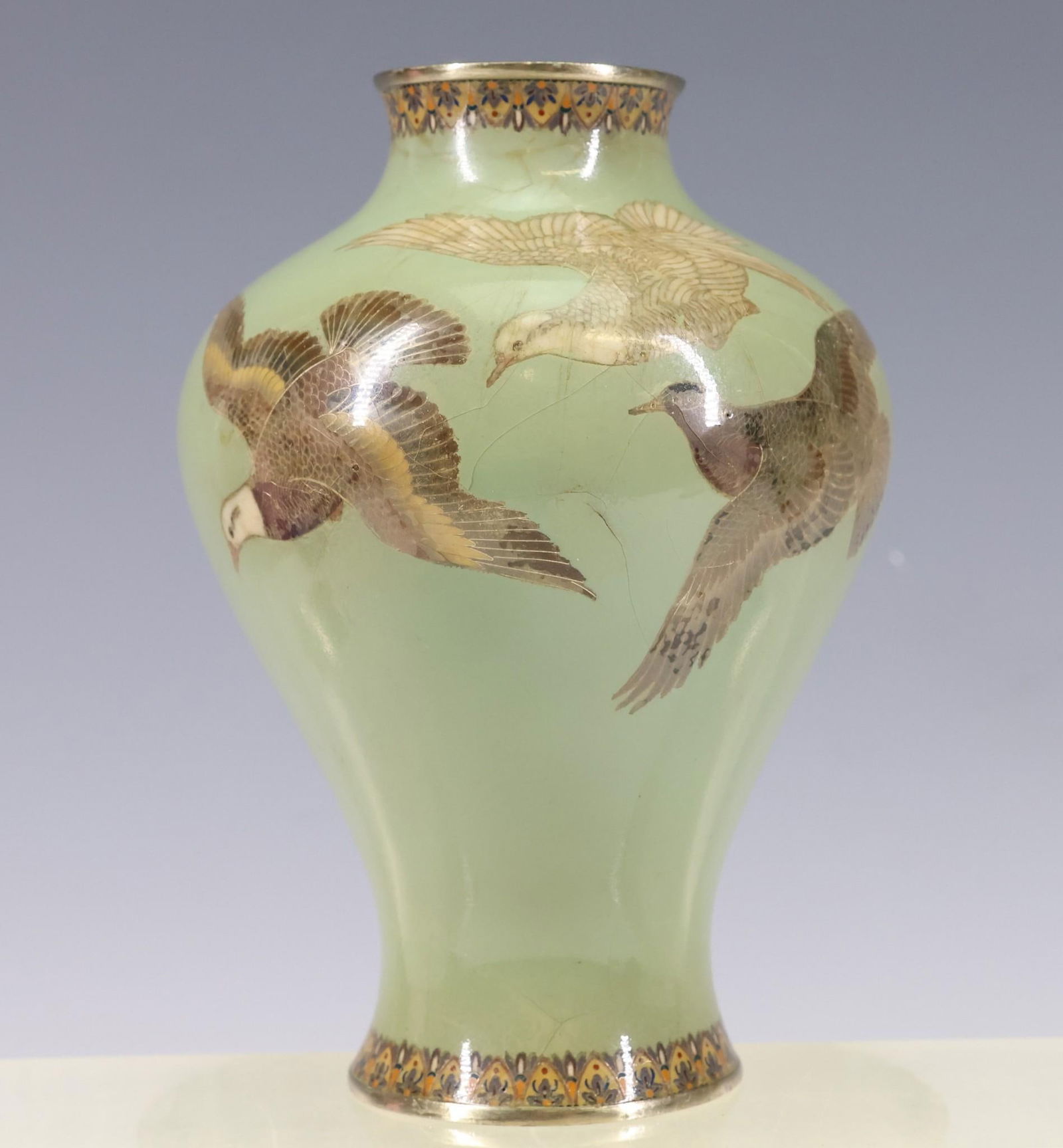 Hayashi Kodenji Japanese Cloisonne Vase: Meiji era vase decorated with birds of prey in flight over a celadon ground with stylized floral borders. Marked to the foot for Hayashi Kodenji (1831 - 1915). Hairlines and discoloration to the ename