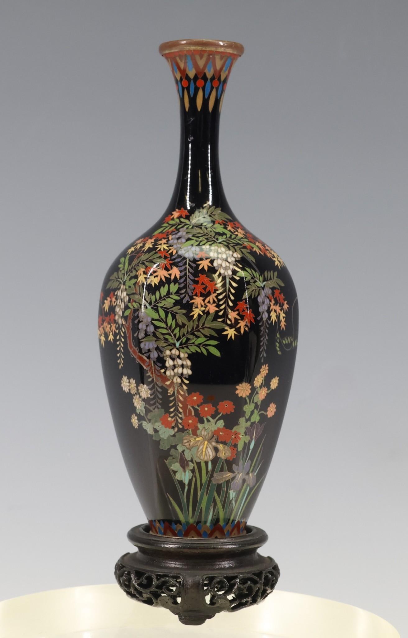Japanese Cloisonne Vase: Meiji - Taisho era scalloped bottle vase depicting a variety of flowers on a black ground with geometric motif borders. Includes a stand. 4.75"h x 2"w