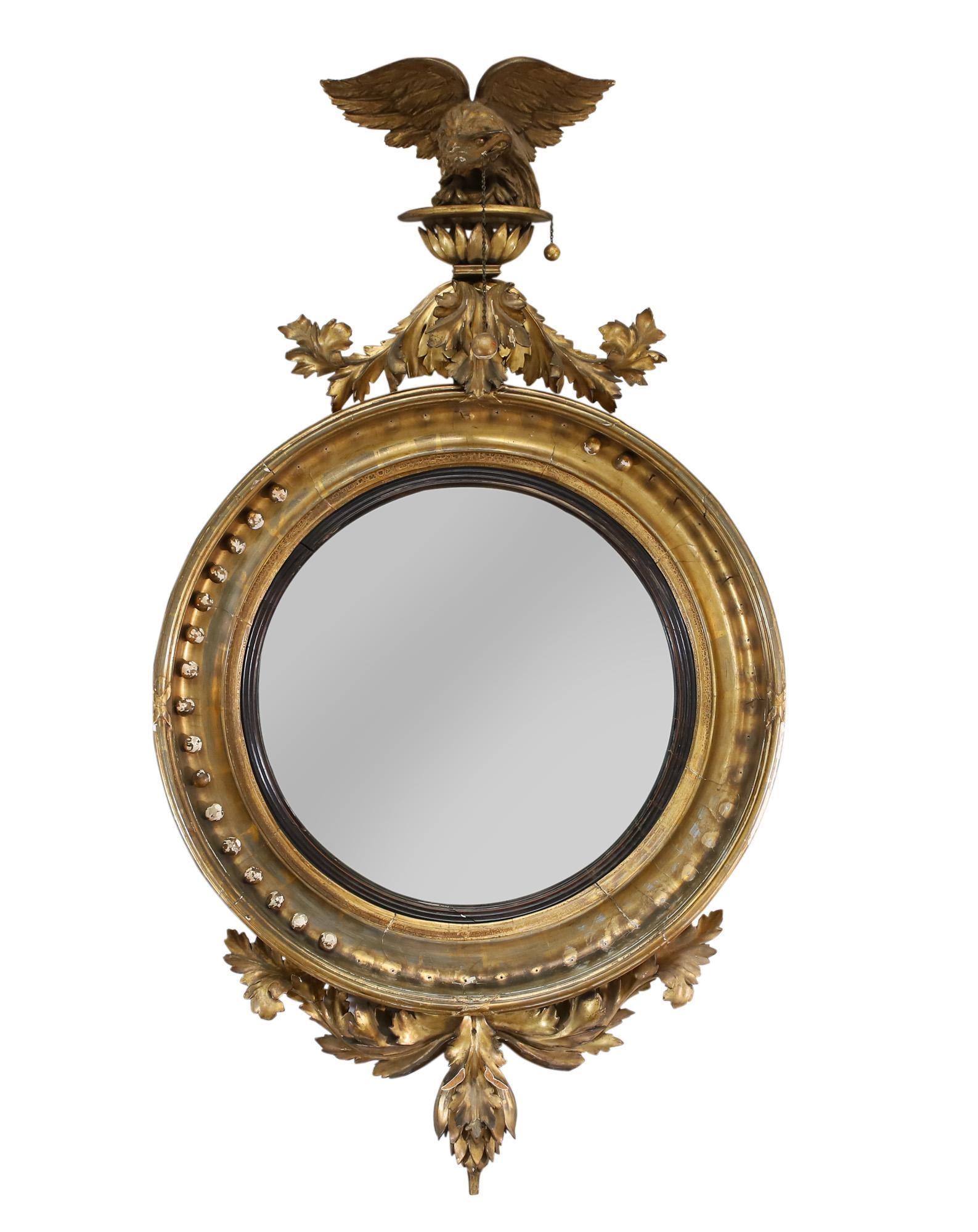 Federal Giltwood Carved Girandole Mirror: Perched carved eagle motif along the top having a ball and chain hanging from the beak, circular mirror with spheres and acanthus leaf decorated apron. Back exhibits remnants of the candle holders and