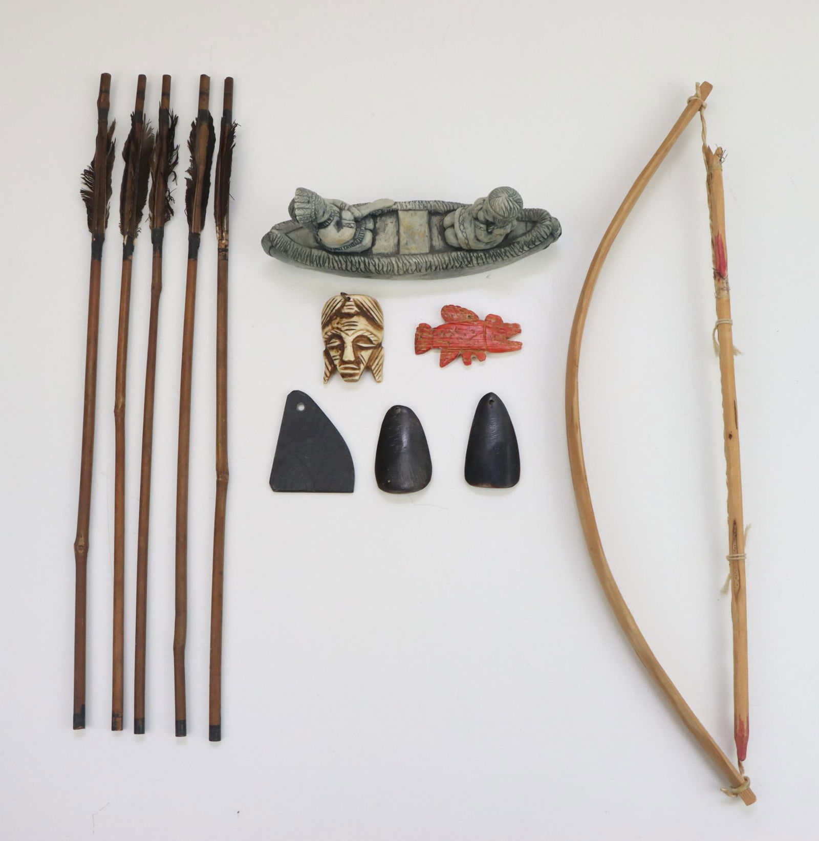 Ethnographic & Contemporary Curios: Horn gorgets (2), bone carved fish pendant, stone gorget. Contemporary 16" hand crafted bow with 5 arrows, bamboo, hand painted, genuine feathers. Contemporary figural, children in canoe, made from vo
