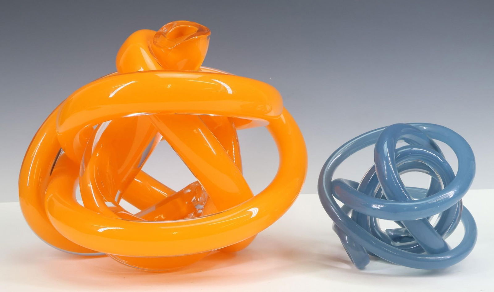 SkLO Art Glass "Wrap" Objects: Czech handblown glass wound tube decorative objects, including "Wrap" in New Blue, and "Wrap Large" in custom orange. "Wrap Large" is labeled. 5"h x 6"w x 5.5"d, and 9"h x 10.5"w x 9"d
