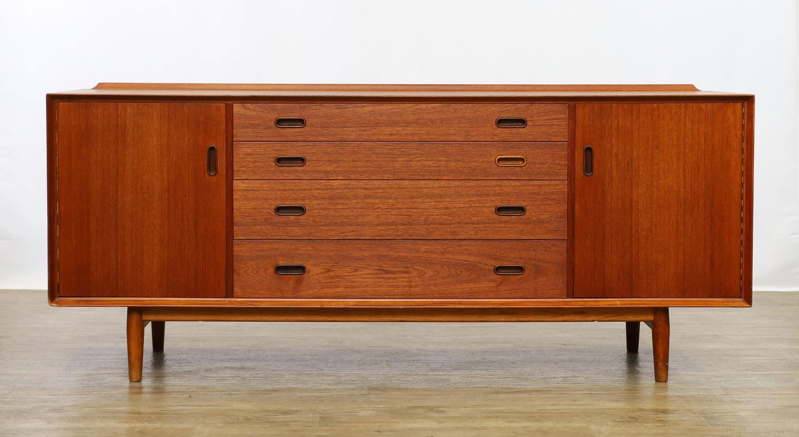 Arne Vodder for Sibast Model OS25 Sideboard: Danish Modern teak sideboard, featuring four graduated drawers flanked by hinged doors which open to maple lined cabinets, each with an adjustable shelf, mounted to a stand with cigar legs, stamp mark