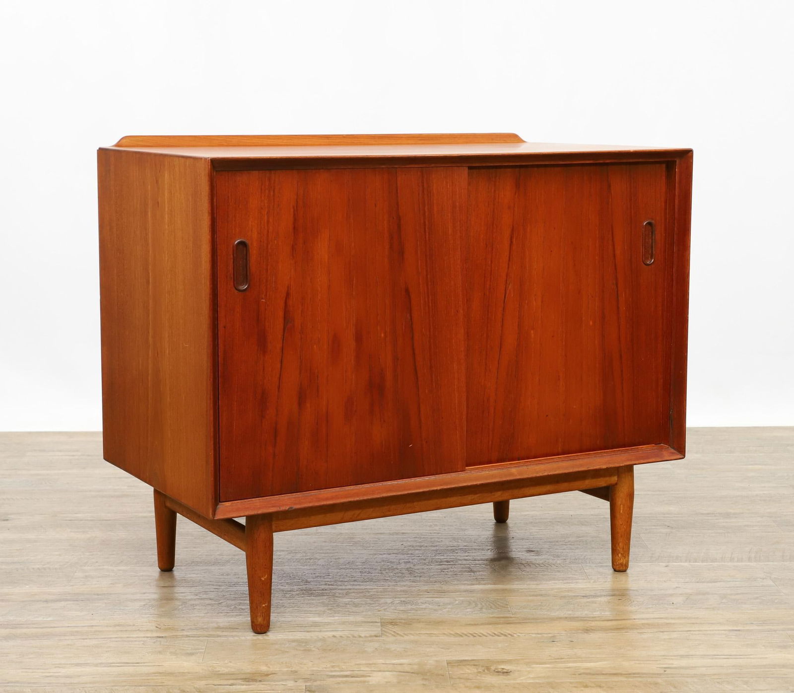 Arne Vodder for Sibast Server: Danish Modern teak server with sliding doors which open to a maple lined cabinet and adjustable shelf, sitting on a stand with cigar legs, stamp marked for Sibast Mobler and importer George Tanier. So