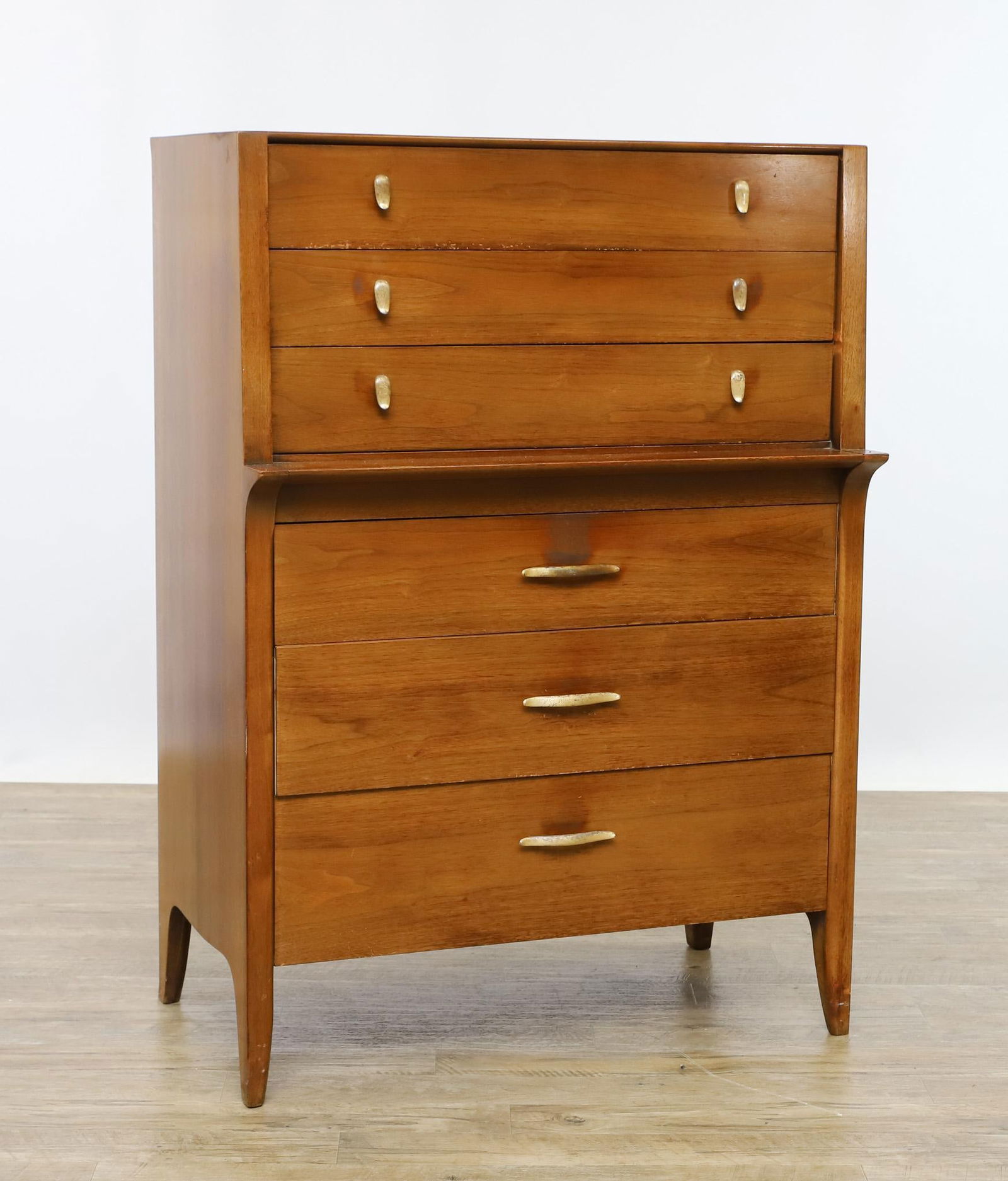 John Van Koer for Drexel Profile Chest: Model K11 walnut chest with three drawers over three graduated drawers, with silver plated pulls in two different designs, on shaped tapered legs, stamp marked. An area of veneer loss to a foot; other