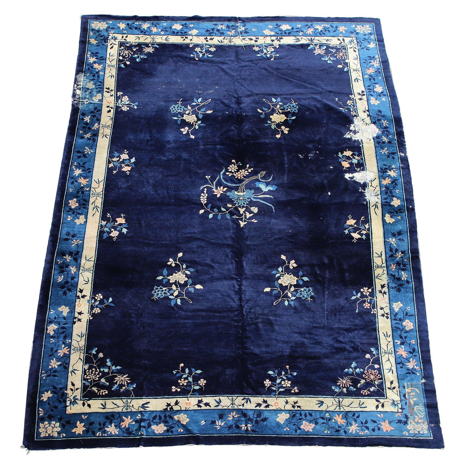 Chinese Art Deco Rug: Hand knotted fine wool rug with floral and vine motifs with field and border colors of dark and light blue, and cream. Rug exhibits areas of moth and pile damage, repairs, and wear. 14'2"l x 10'w