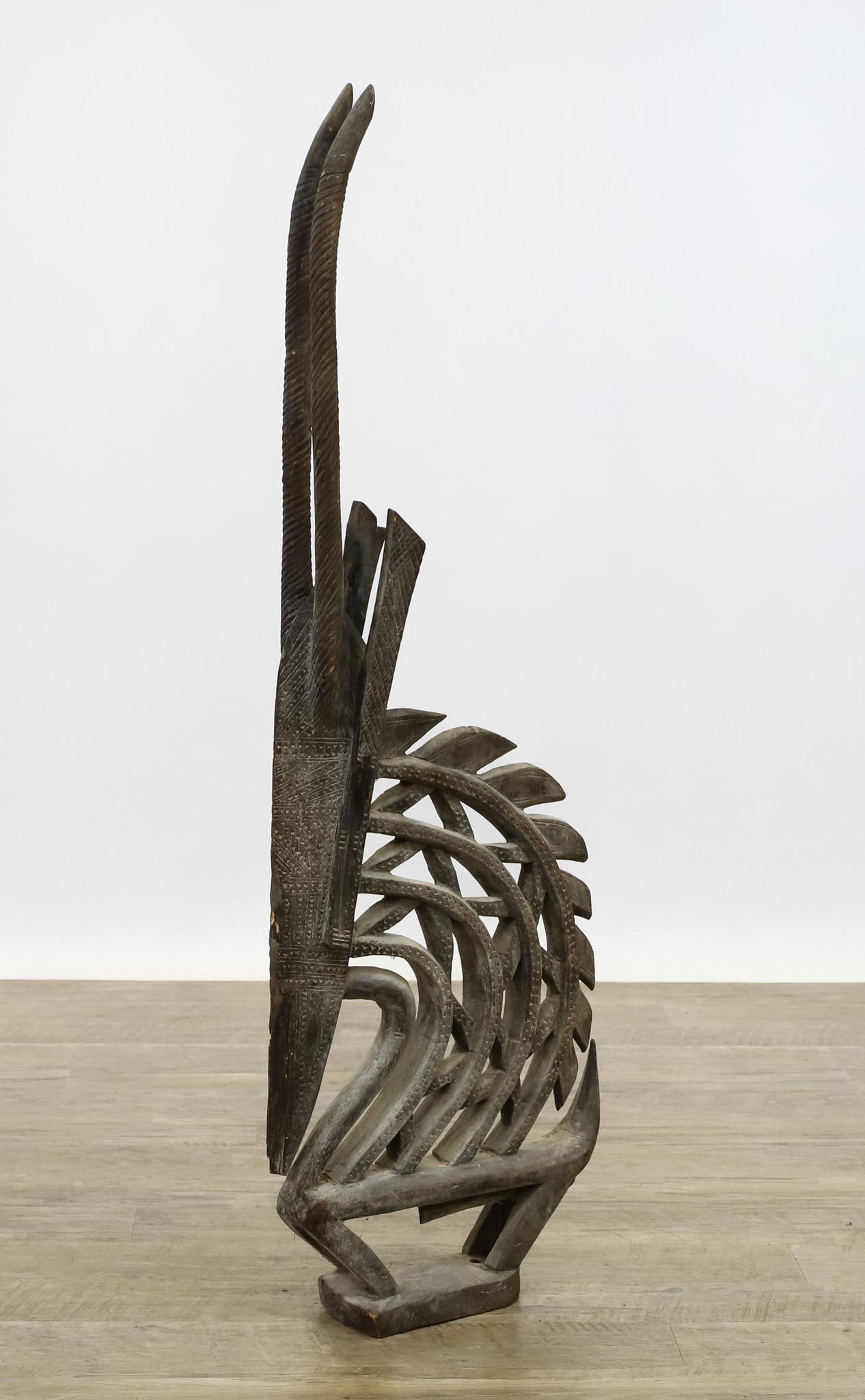Bambara Chiwara Antelope Headdress: West African carved hardwood headdress in the form of an abstract male antelope with chip carved decoration. Circa 19th C. 42"h x 14"w