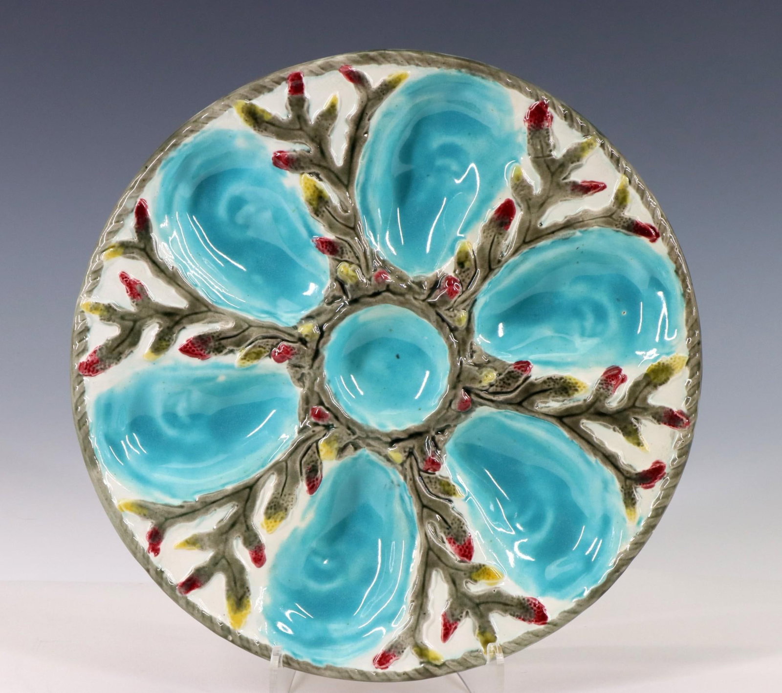 S. Fielding Majolica Oyster Plate: British majolica oyster plate, six oyster shell form turquoise wells surrounding a round turquoise well with seaweed decoration on a white ground. Marked 64, no manufacturers markings noted. Late 19th