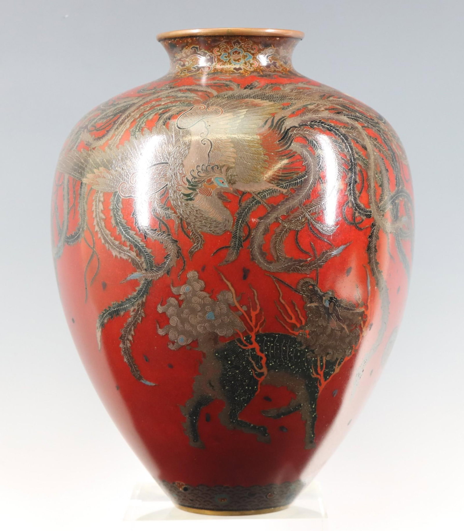 Japanese Cloisonne Vase: Meiji - Taisho era silver wire cloisonne vase depicting a phoenix and a kirin chasing a flaming pearl, on a blood red ground, the upper border with a goldstone floral motif, the lower border depicting